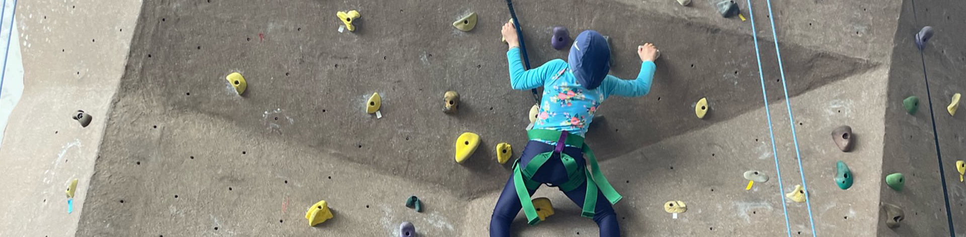 Narjis climbs a rock wall.